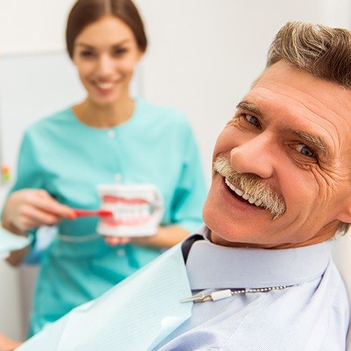 Older man smiling during dental checkup and teeth cleaning visit
