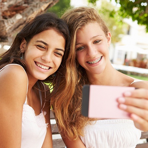 Two smiling teen girls one with traditional braces