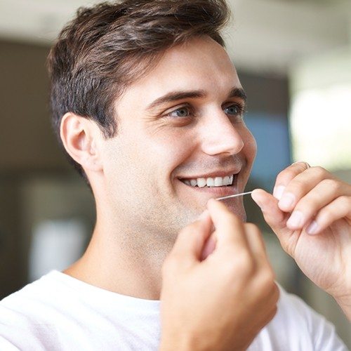 Man flossing to maintain oral hygiene