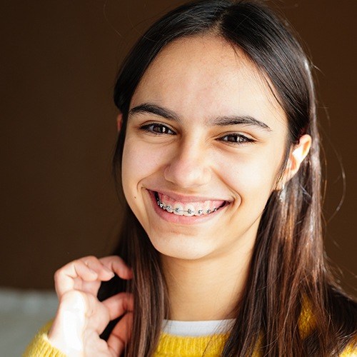 Young woman with traditional orthodontics smiling