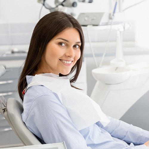 Female dental patient sitting in chair and smiling