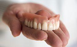 Hand holding a full denture