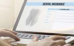 Person using laptop to purchase dental insurance