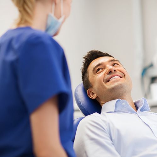 Man smiling at dental team member after receiving tooth colored fillings