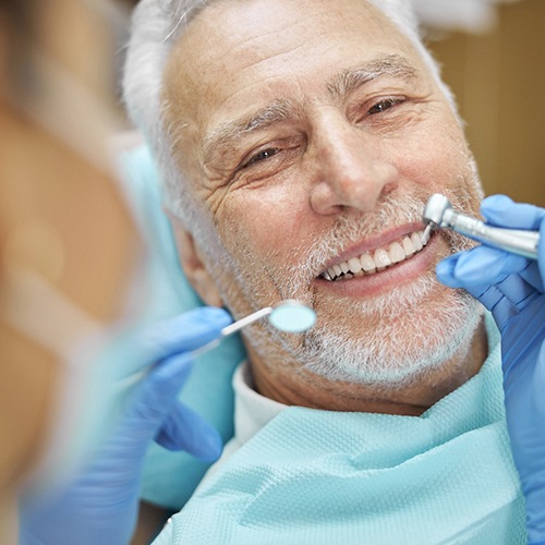 Older man smiling while visiting implant dentist in Lacey