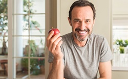 Smiling man with dental implants in Lacey holding an apple