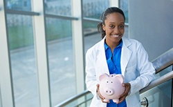 Dentist holding piggy bank in Lacey