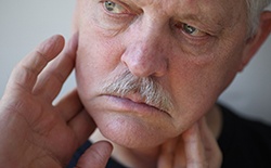 older man touching jaw after dental implant surgery in Lacey 
