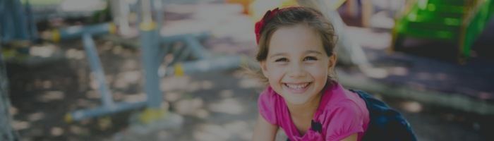 Young girl grinning at outdoor playground