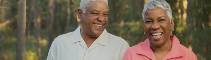 Older man and woman smiling among trees