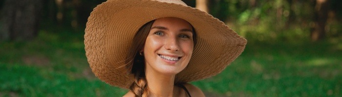 Young woman in sunhat grinning outdoors