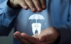 Hand holding an animated tooth under an umbrella