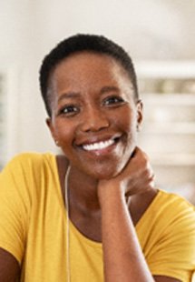 Woman in yellow shirt smiling while relaxing at home