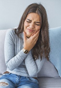 Closeup of woman on couch struggling with toothache