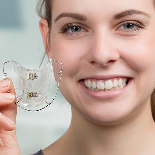 Smiling patient holding a retainer