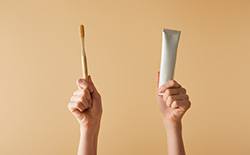 Two hands holding a toothbrush and toothpaste