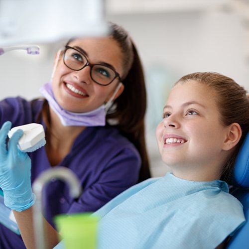 Dental team member and young patient discussing the process of getting dental sealants