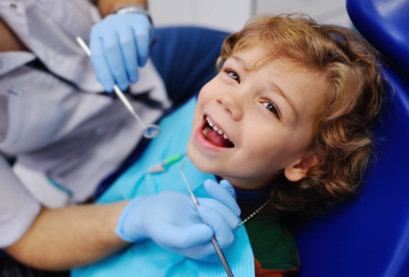 a little boy smiling while preparing to undergo a dental checkup and cleaning