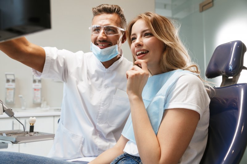 A young woman listens as her dentist explains what is visible on the nearby monitor