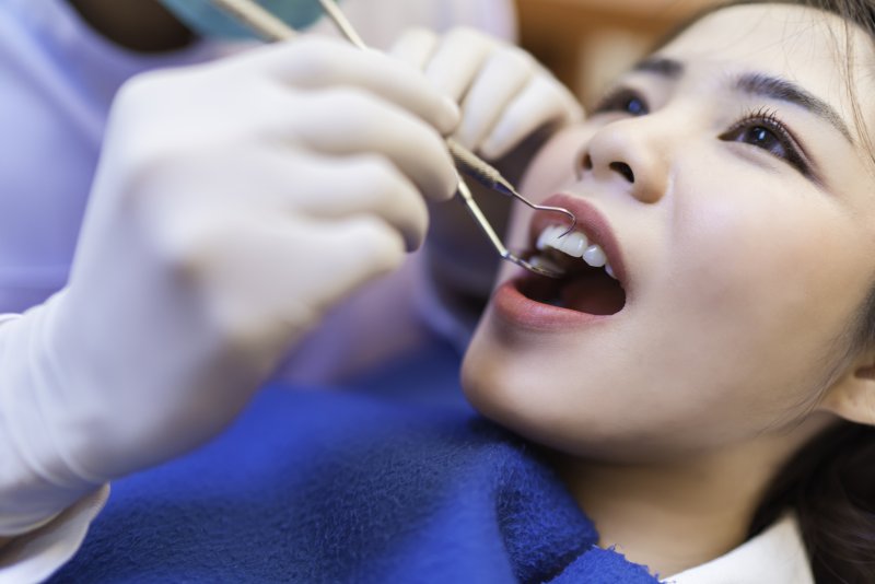 a patient having their teeth checked by a dental professional wearing gloves