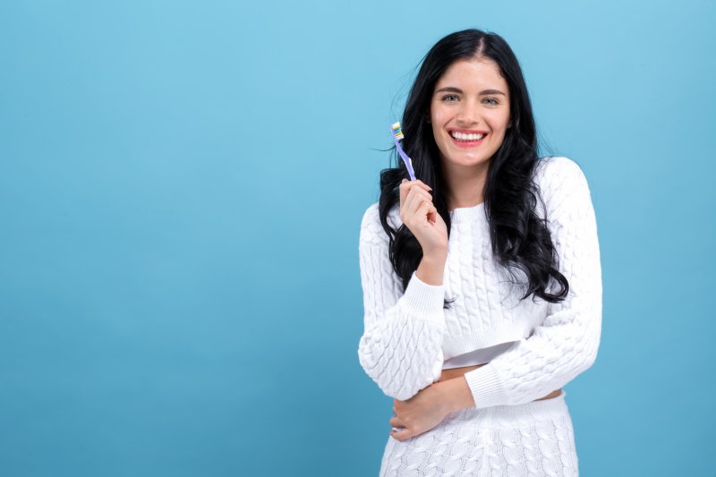 a young woman holding a manual toothbrush in her hand