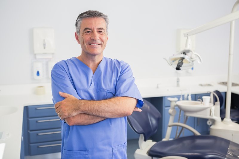 a male dentist wearing his scrubs inside a treatment room