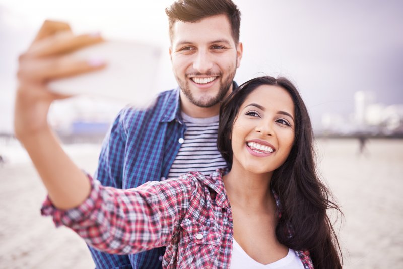 A girl and guy smiling for a photo on the beach